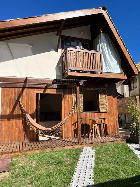 a house with a deck and a hammock in the yard at Cabana na Natureza Com Hidro - Baoba Suites in Bombinhas