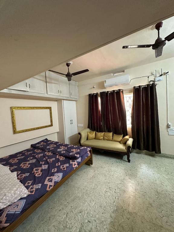 a bedroom with a bed and a couch and a window at Rose villa in Coimbatore