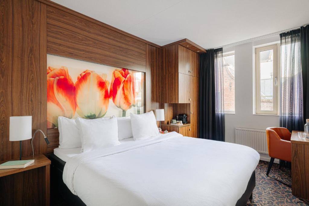 una habitación de hotel con una gran cama blanca con una pintura de flores en Leonardo Eden Hotel Amsterdam City Center, en Ámsterdam