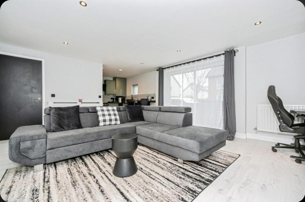 Stunning, Newly Refurbished 1-Bedroom Flat in Gravesend في غريفسيند: غرفة معيشة مع أريكة رمادية ونافذة كبيرة