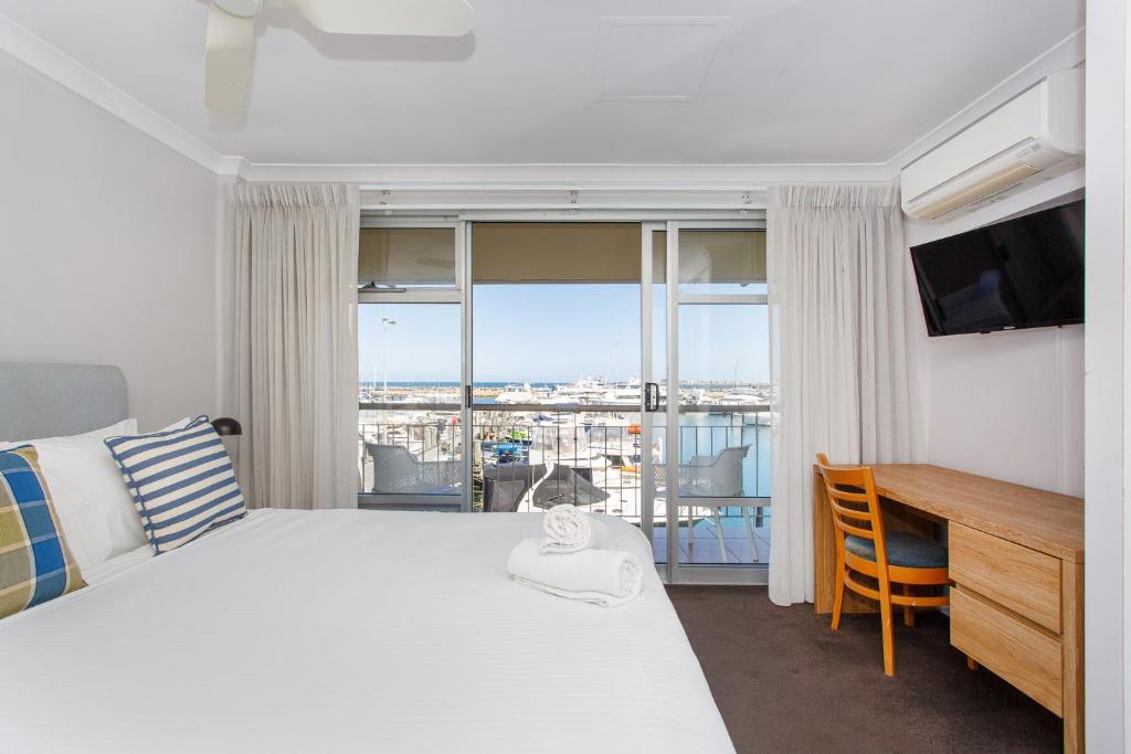 a bedroom with a bed and a desk with a television at Sunset Marina Escape Freo-amazing Views & Central in Fremantle