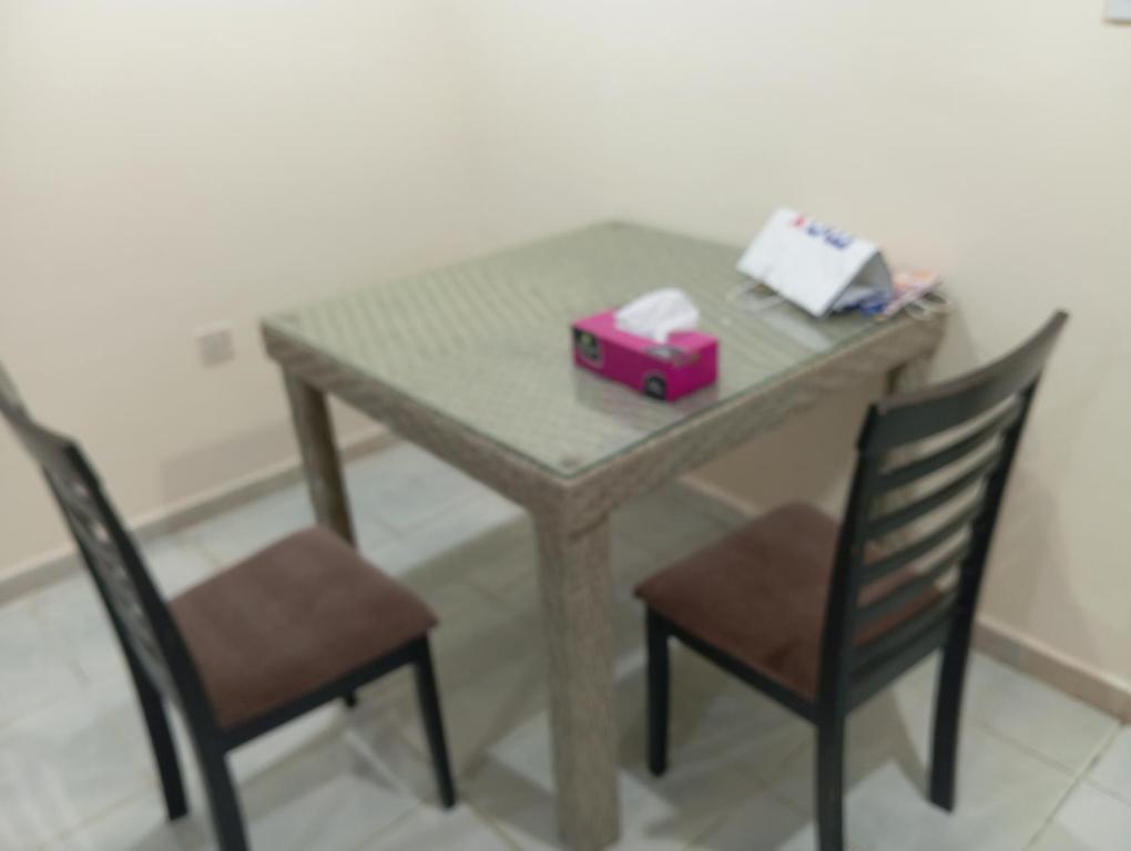 een tafel met twee stoelen en een roze doos erop bij Happy living room stay in Sharjah