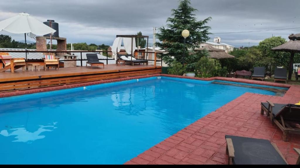 a large blue swimming pool with chairs and a table at Del valle cabañas in Tanti