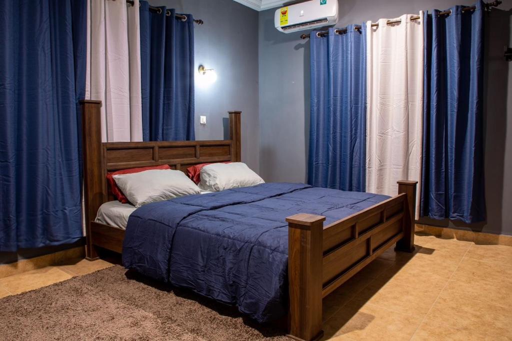 a bedroom with a bed with blue sheets and blue curtains at Bluegreen Guest House in Accra