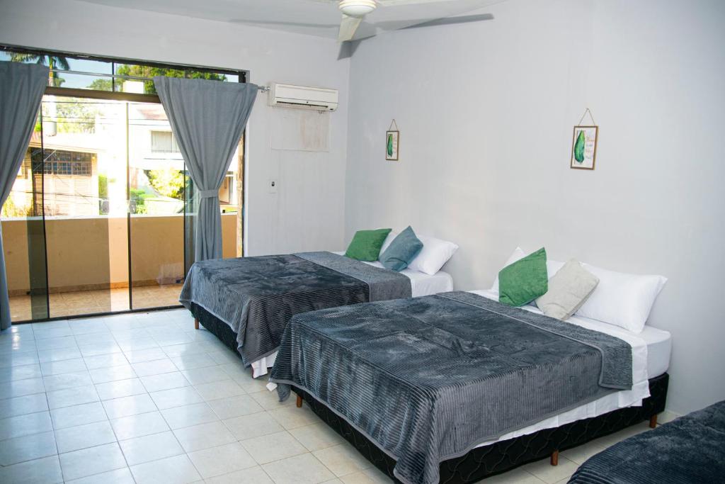 two beds in a room with a window at GuestHouse Encanto del Centro in Encarnación