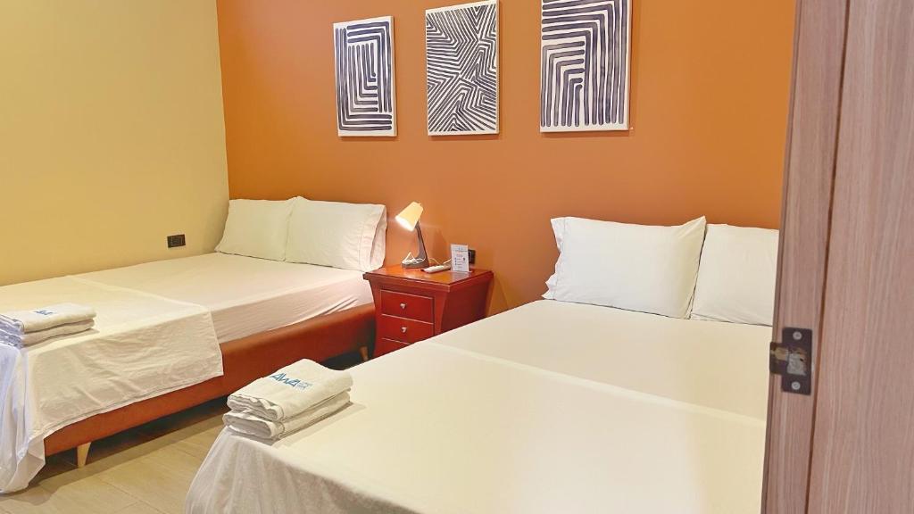 a room with two beds and a nightstand with two beds at Awa House Hotel in Aguachica