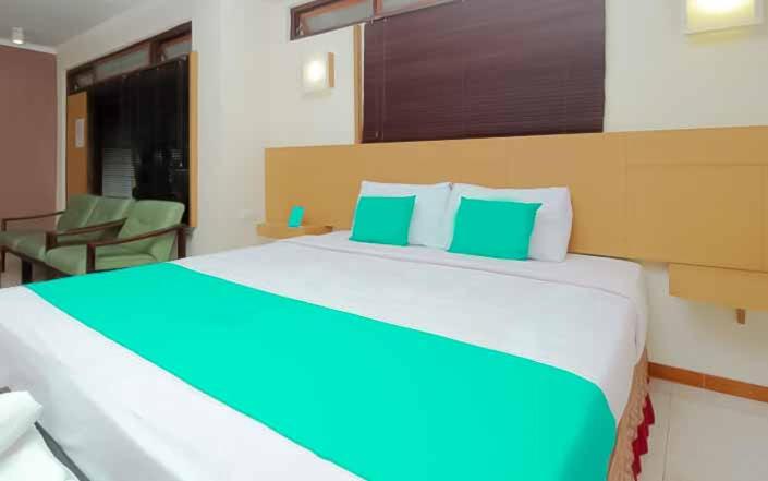 a bedroom with a large bed with green and white pillows at Hotel Lestari Near Lippo Plaza Mall Jember in Jember