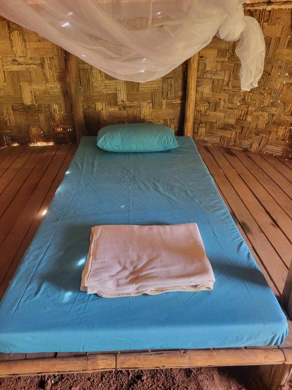 ein Bett in einer Holzhütte mit einem Zelt in der Unterkunft Twelve107 Farmstay in Krong Saen Monourom