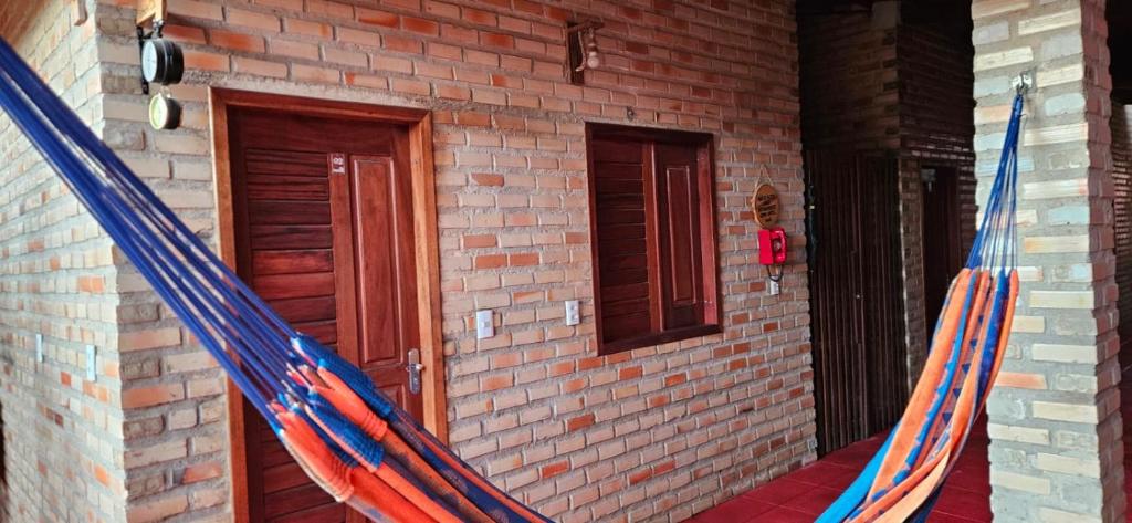 Een hangmat hangt buiten een bakstenen gebouw. bij Chalé Viçosinha de Açúcar in Viçosa do Ceará