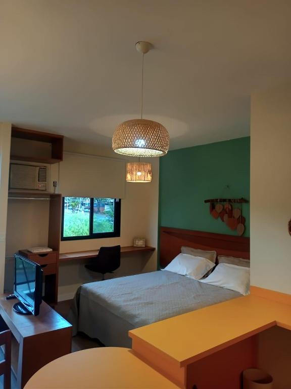 a hotel room with a bed and a desk at Flat Montese Tower Resende - Refúgio na Serra da Mantiqueira, Próximo à AMAN e Penedo in Resende