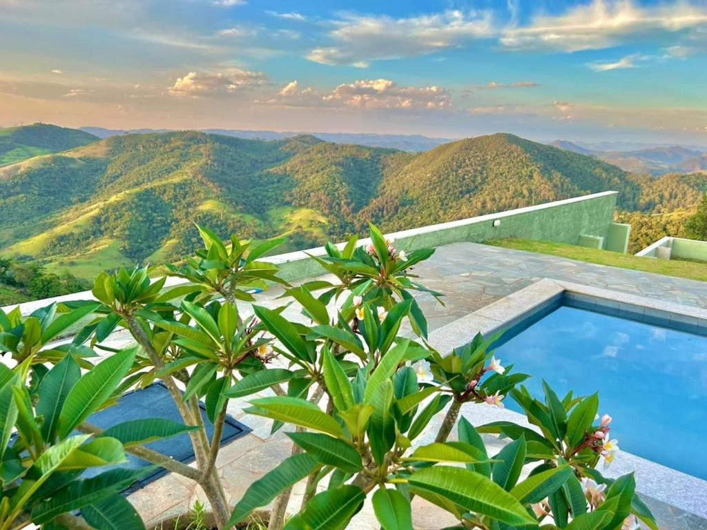 a swimming pool on top of a mountain with trees at Casa La Vigie in Águas de Lindoia