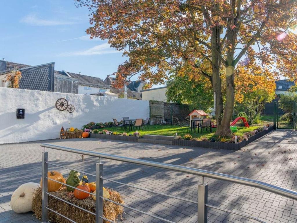 Holiday home Ahorn, 1st floor في Weilerswist: حديقة بها قرع على رصيف بجوار شجرة