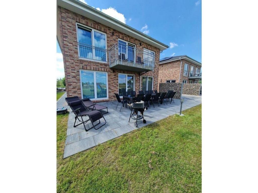 a patio with chairs and tables in front of a building at Holiday home Ebbe with dog up to 14 people in Schülp