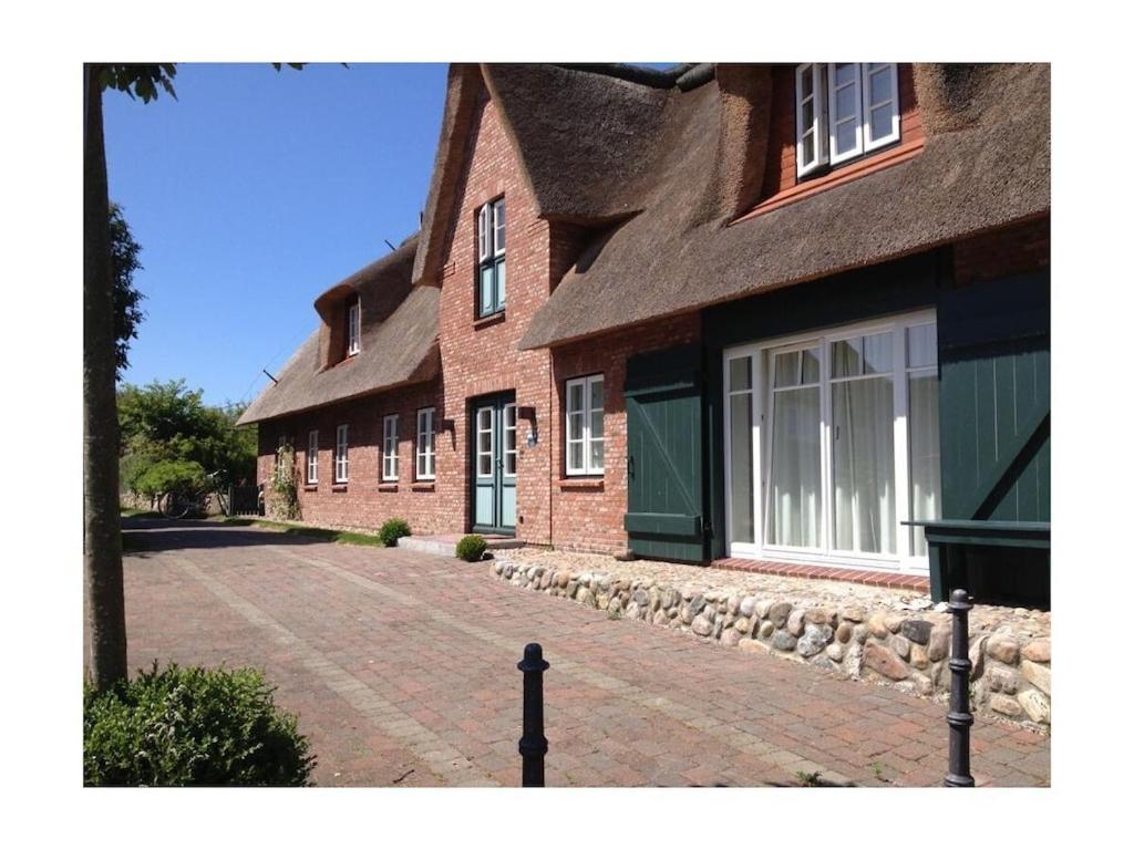 ein großes Backsteinhaus mit einer Auffahrt davor in der Unterkunft Holiday home property 46 in Utersum