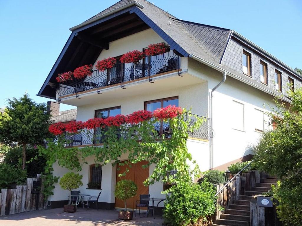 a white house with red flowers on the balcony at 2 Weinhaus Marmann in Osann-Monzel