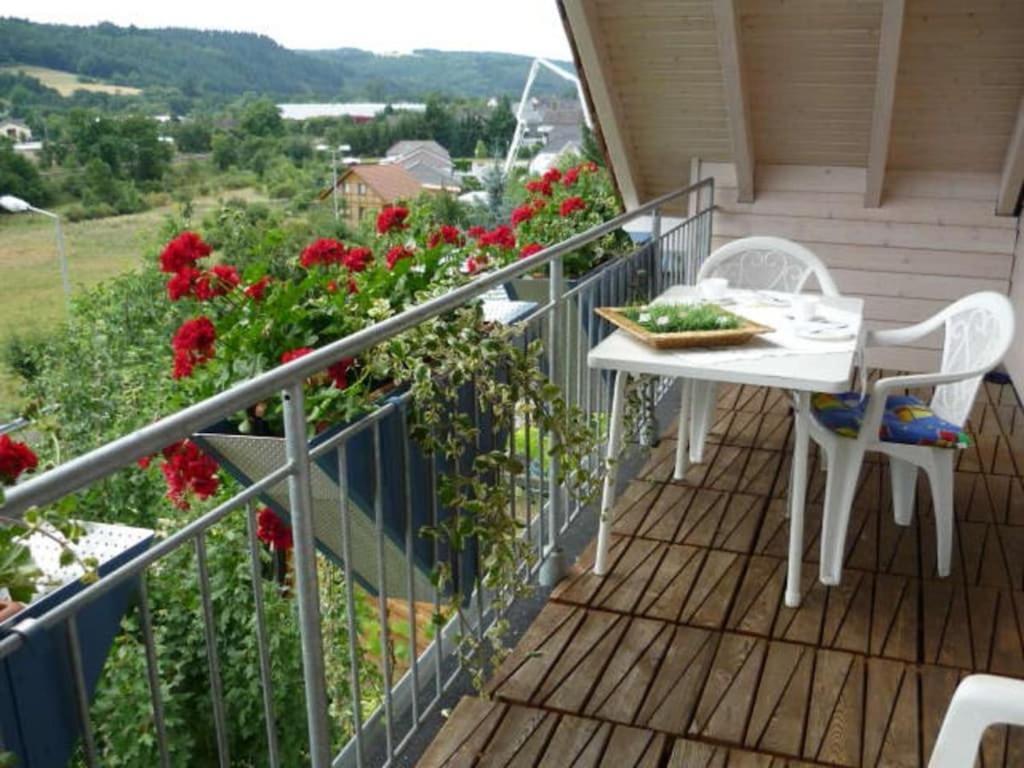 a balcony with a table and chairs and flowers at Close-up view inside the Vorbek house in Bärenbach