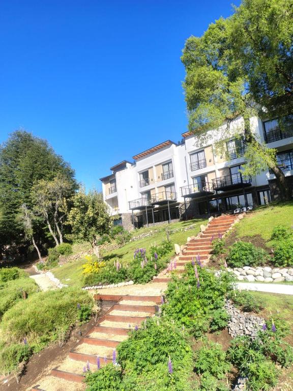 a building with stairs in front of a garden at Aparts y Cabañas Costa de Lago in Villa Pehuenia
