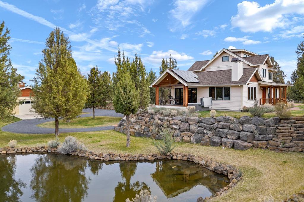 a house with a stone wall and a pond at High Lowe in Bend