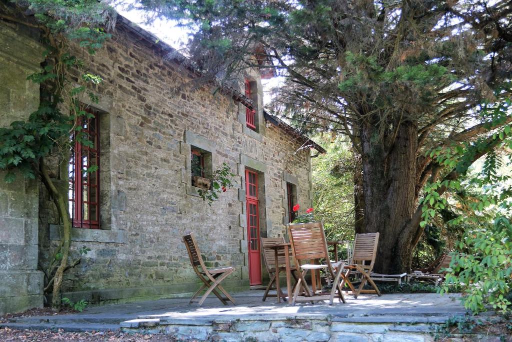 a brick house with chairs and a red door at Cottage du Manoir de Trégaray in Sixt-sur-Aff