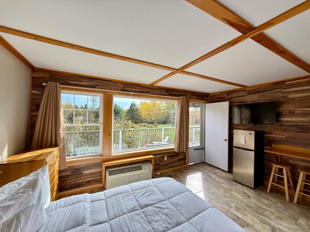 a bedroom with a bed and a large window at Eden Village Motel and Cottages in Bar Harbor