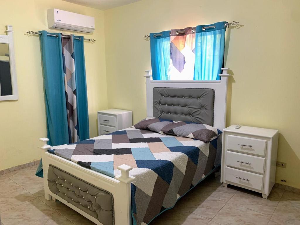 een slaapkamer met een bed en blauwe gordijnen bij Tu Casa En Pedernales in Pedernales