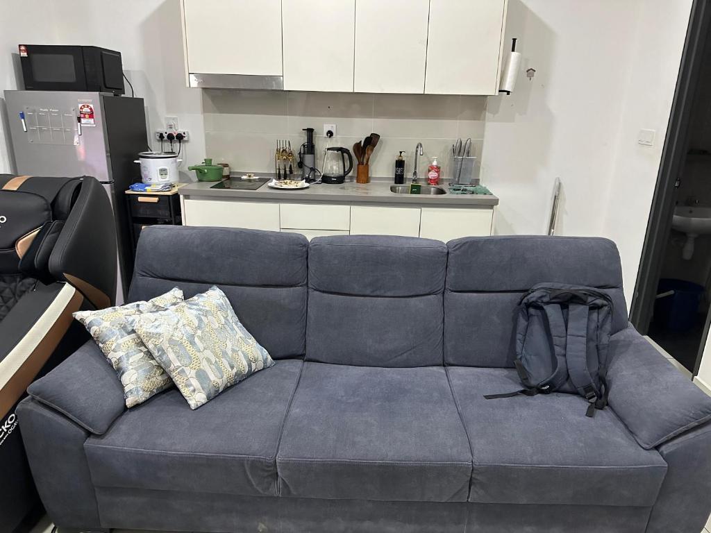 シャー・アラムにあるVinThris HomeStayのキッチンに置かれた青いソファとリュックサック