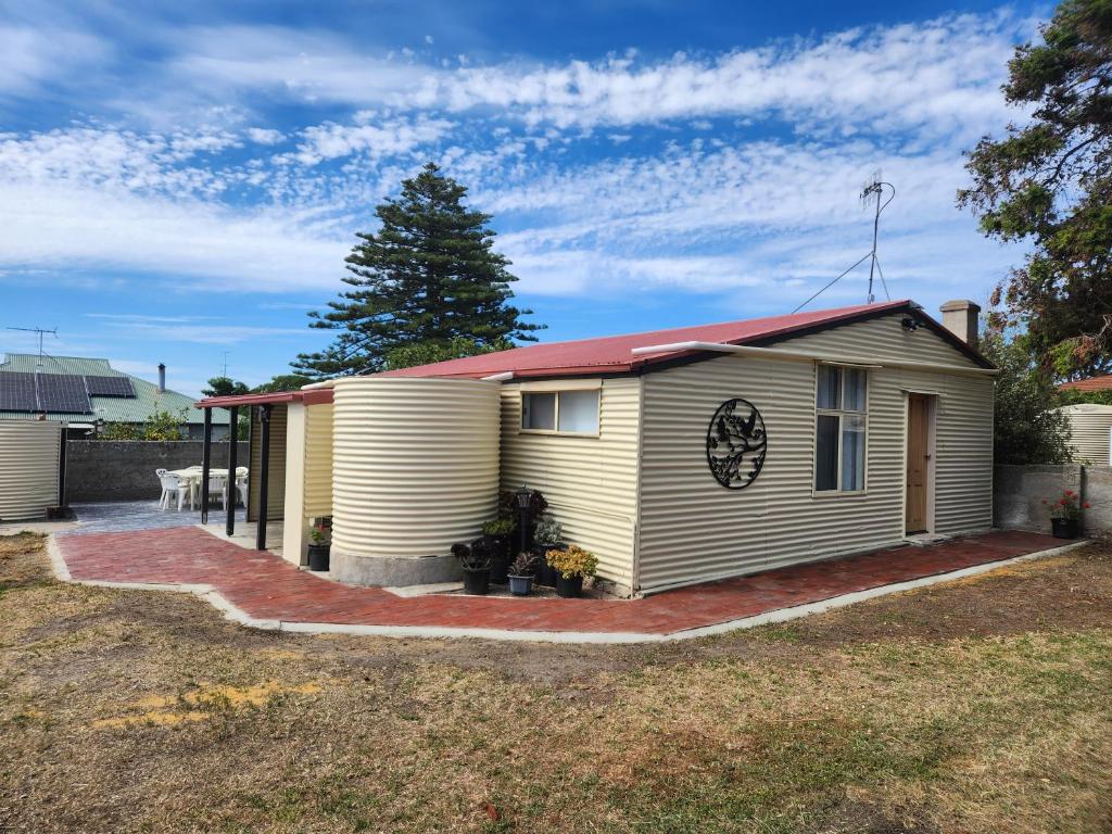 Jack's Shack Kingscote في كنغزكوت: منزل اصفر صغير بسقف احمر