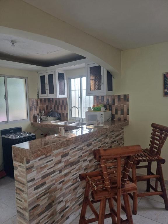 uma cozinha com um balcão e duas cadeiras de madeira em Dona Beba Guesthouse em La Caleta