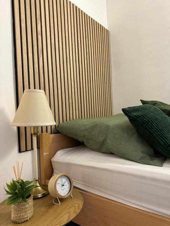 een bed met groene kussens en een klok op een tafel bij HouseofGeneration in Stuttgart