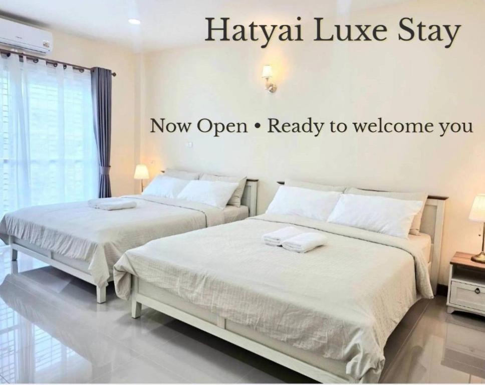 two beds in a hotel room with the wordsanya luxury stay at Hatyai Luxe Stay in Hat Yai