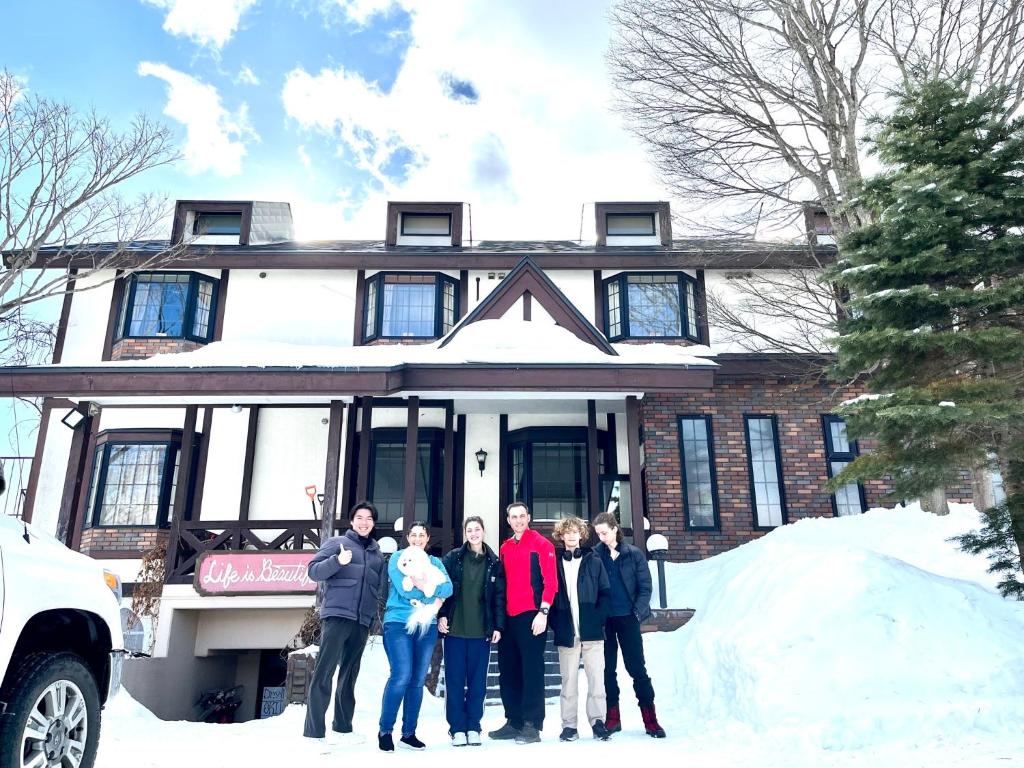 a group of people standing in front of a house in the snow at Appi Life is Beautiful in Hachimantai