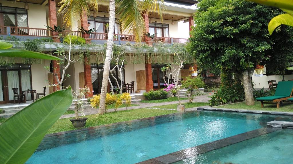 a swimming pool in front of a building at Nyoman Sandi Guest House in Ubud