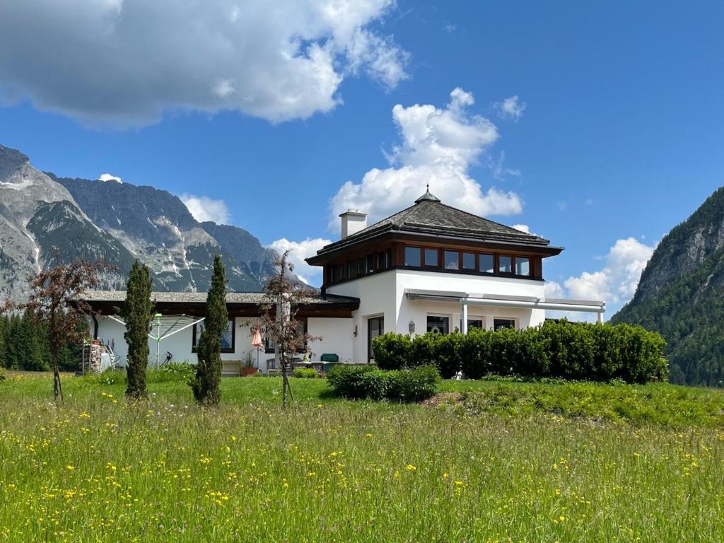 a house in a field with mountains in the background at Chalet Leutasch with Ski Trail & Mountain Views in Leutasch