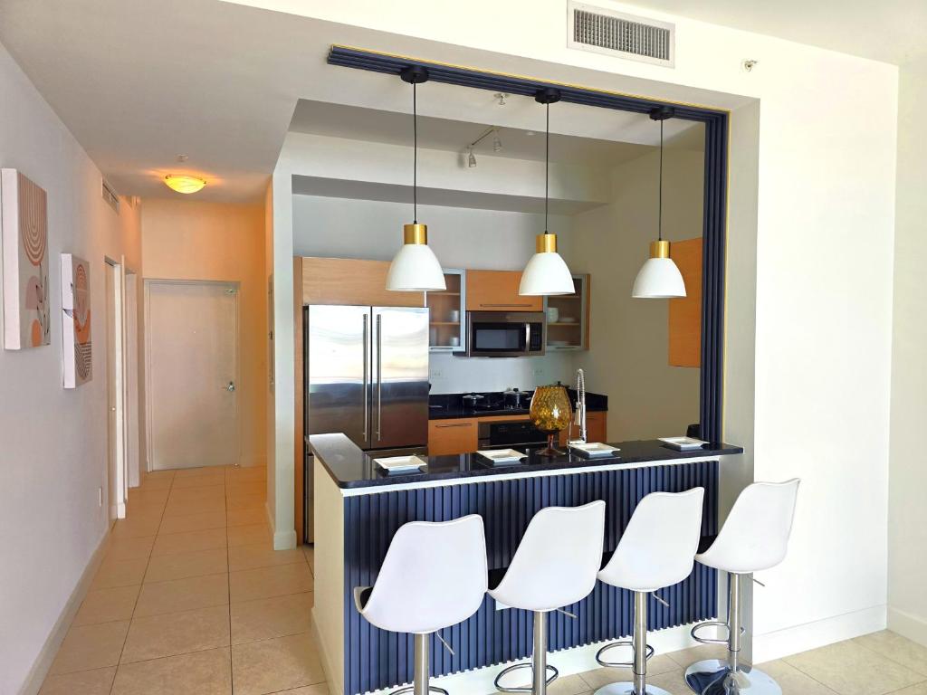a kitchen with a counter with white chairs in it at Lux Vista Retreat, 2BR, 2BA with terrace and pool in Fort Myers