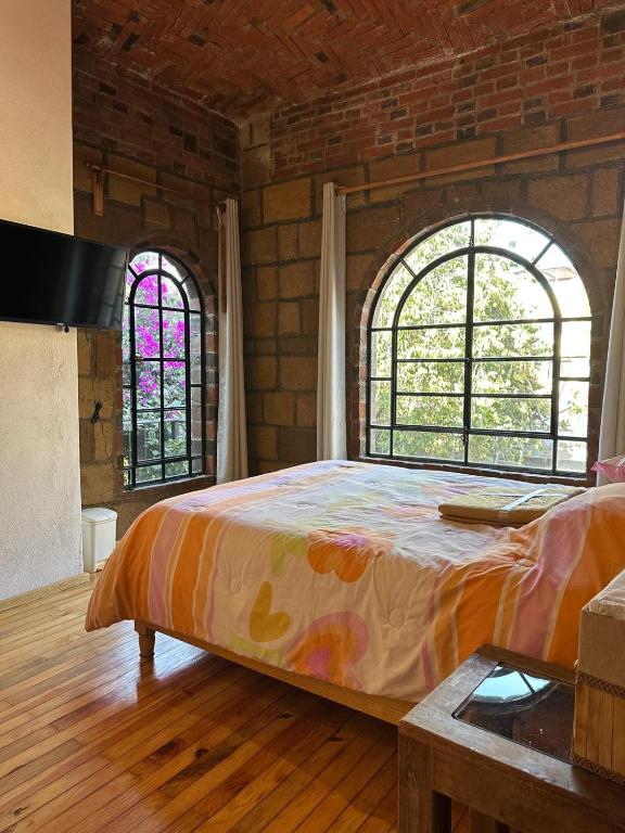a bedroom with a large bed and two windows at Casa Rústica del pedregal in Mexico City