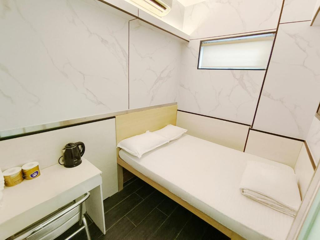 Habitación pequeña con cama blanca y ventana en Joy Hella Inn, en Hong Kong