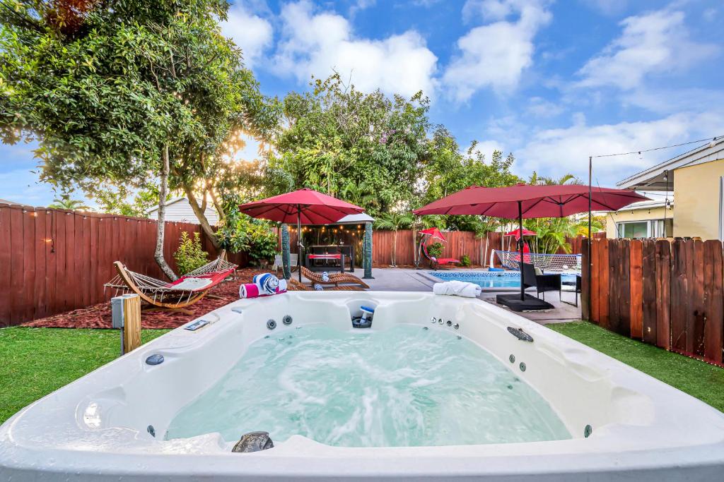 a large hot tub in a yard with umbrellas at Relax at Serenity Heated Pool Spa BBQ Near Beach in Palm Beach Gardens