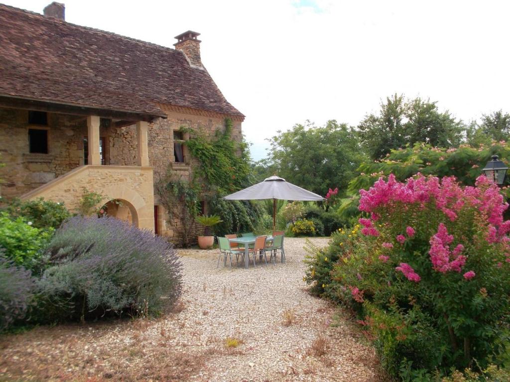 un jardín con mesa, sombrilla y flores en Charmante maison Périgord avec piscine privée et WIFI - FR-1-616-511, en Fonvielle
