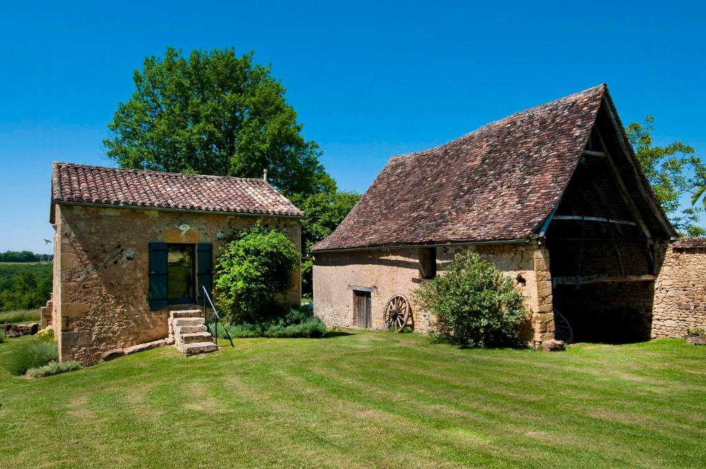 ein altes Steinhaus mit einem großen Rasenplatz in der Unterkunft Charming Mas With Medieval Church Views in Sainte-Croix-de-Beaumont
