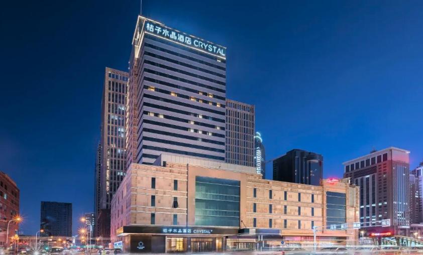 a tall building in a city at night at Orange Crystal Hotel Shenyang North Station in Shenyang