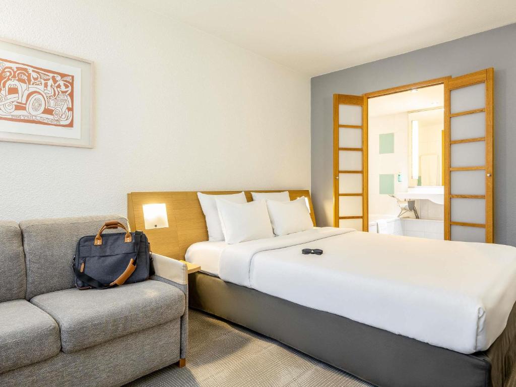 a hotel room with a bed and a couch at Novotel Brussels Airport in Diegem