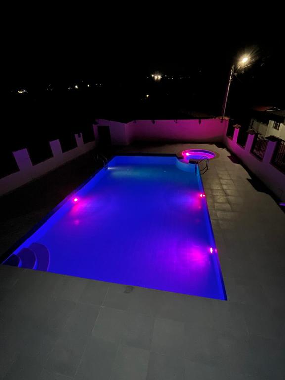 Finca Fusagasugá Villa Luisa في فوساغاسوغا: مصباح سباحة ضوء في الليل مع أضواء أرجوانية