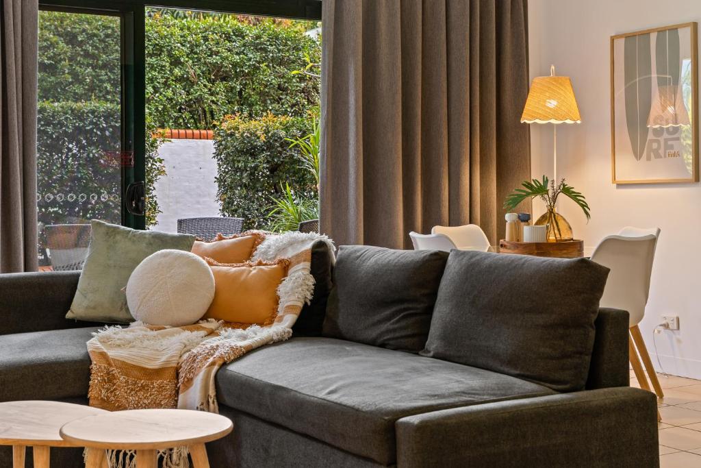 a living room with a gray couch with pillows on it at Byron Getaway @the Crest in Byron Bay