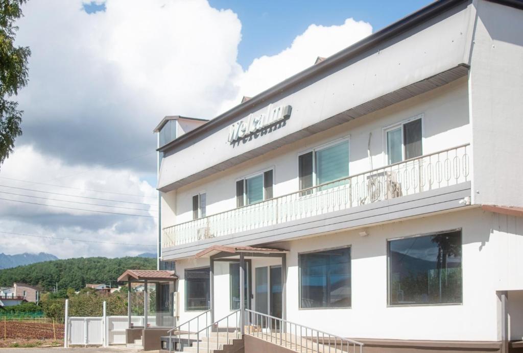 een wit gebouw met een bord erop bij welcalm village in Naemulch'i-ri