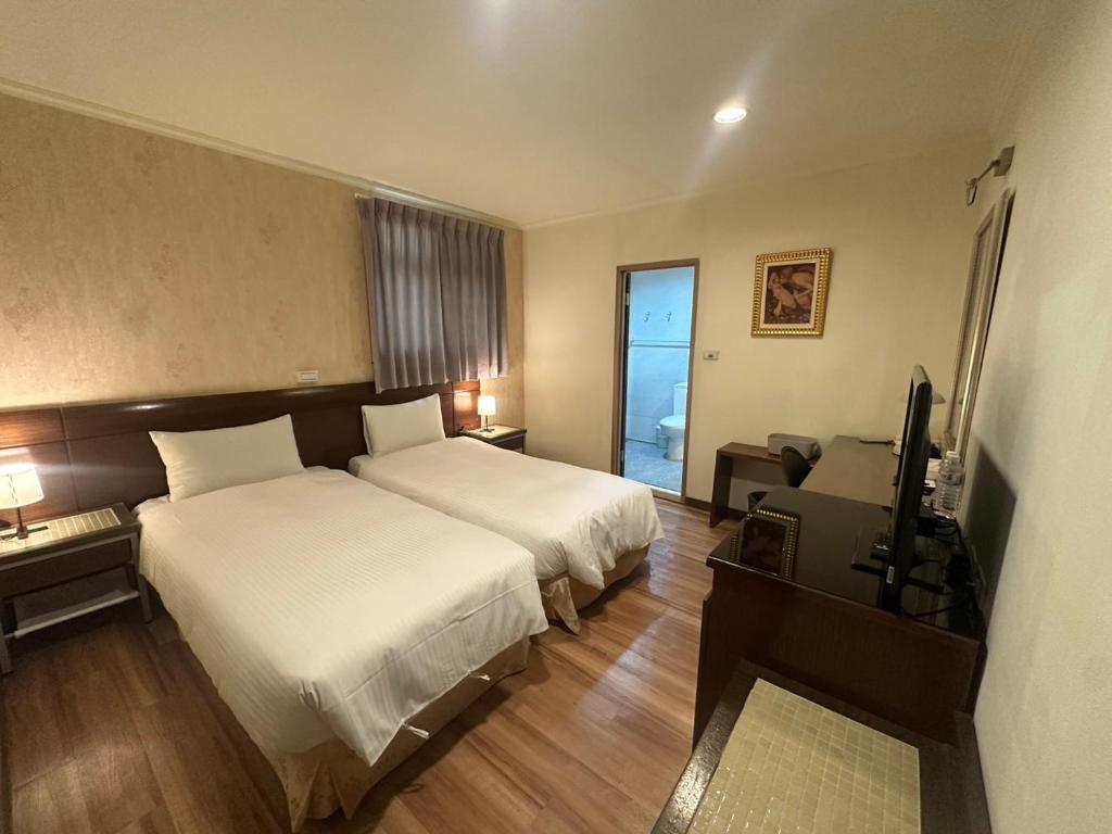a hotel room with two beds and a television at 文化信然 in Tainan