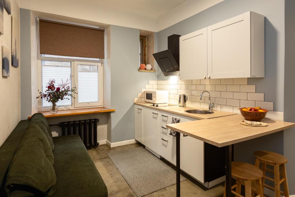 a kitchen with white cabinets and a couch in a room at Baltic Design Apartments with free Parking and self check in in Rīga