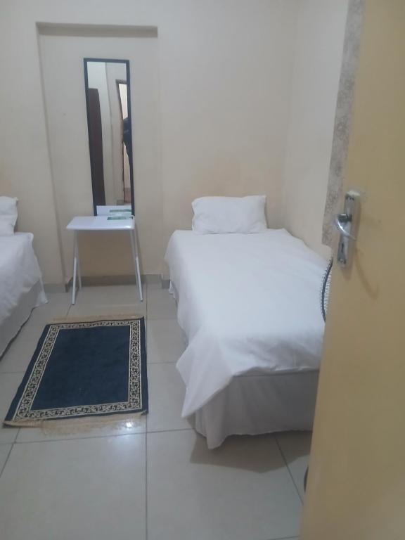 a white bedroom with a bed and a mirror at Clark lodge at 272 in Durban