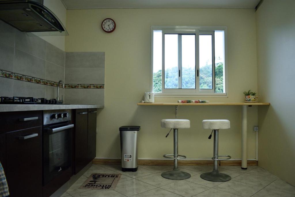 een keuken met 2 barkrukken en een raam bij Le coin tranquille in Saint-Denis