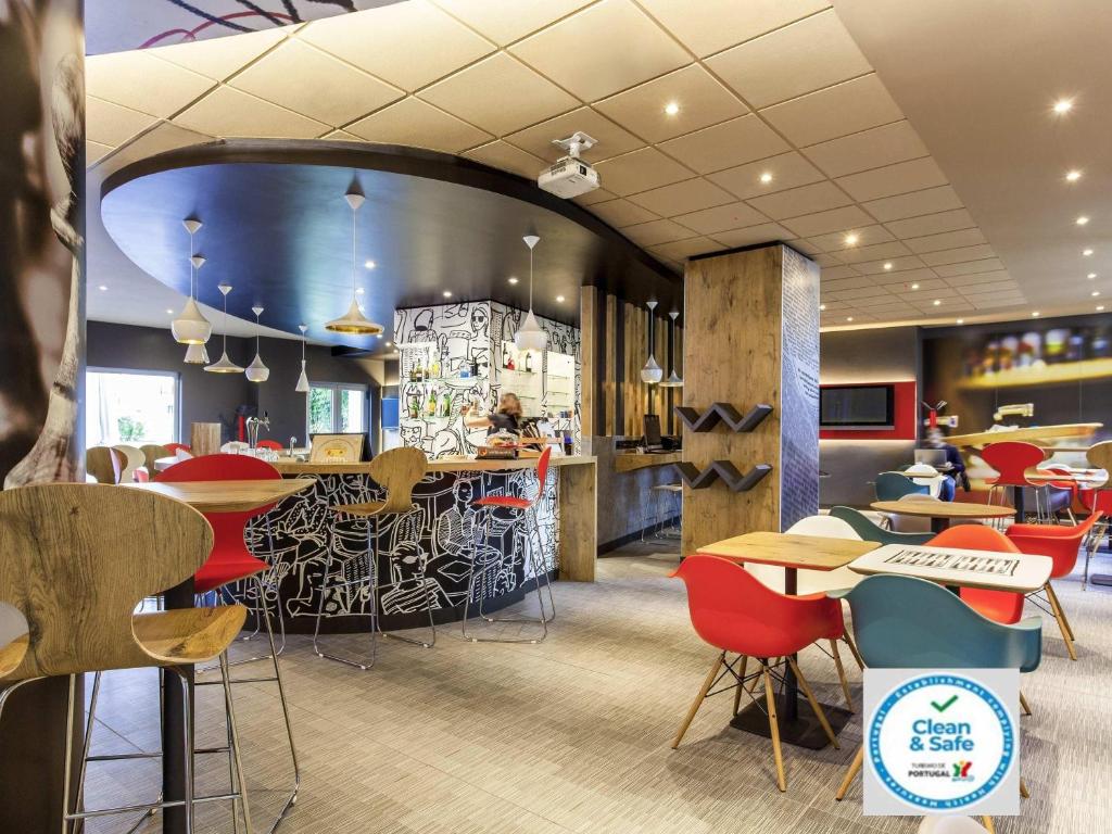 Un restaurante con barra, mesas y sillas. en Hotel ibis Lisboa Jose Malhoa, en Lisboa