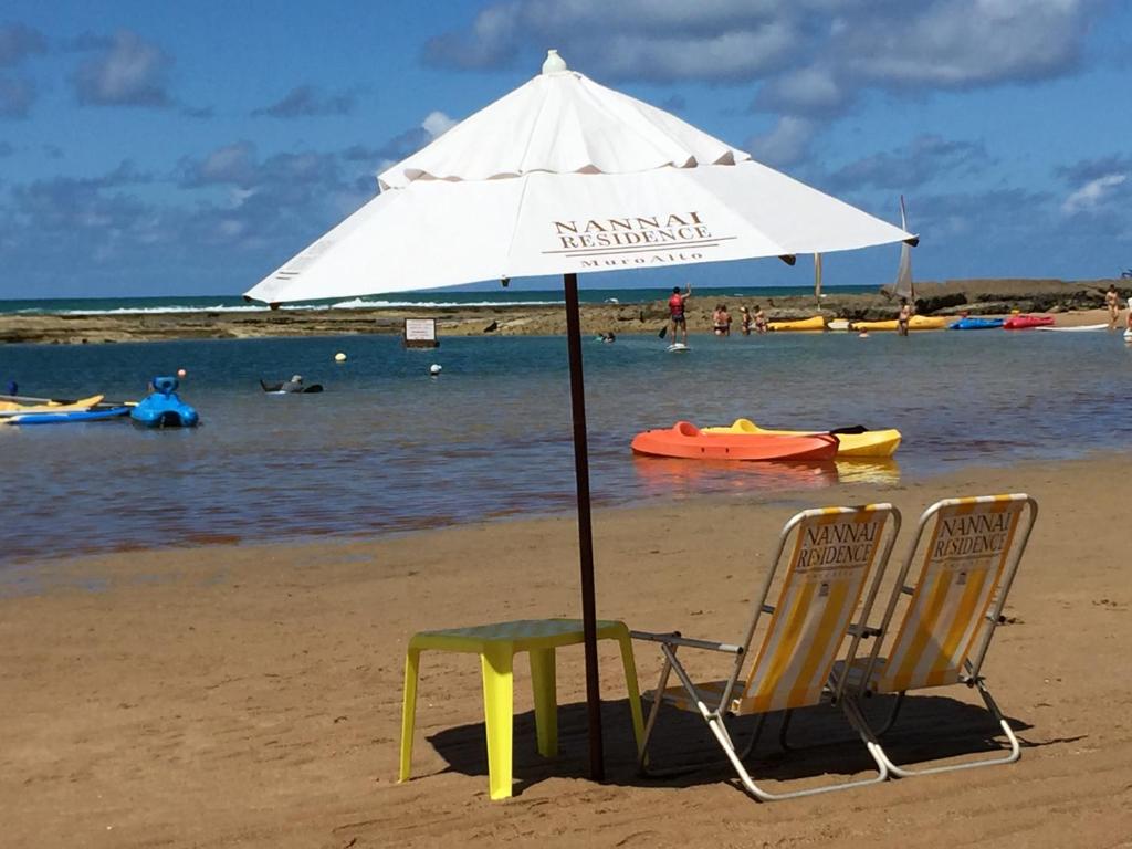two chairs and an umbrella on the beach at Nannai Beira Mar Porto de Galinhas 307 in Porto De Galinhas